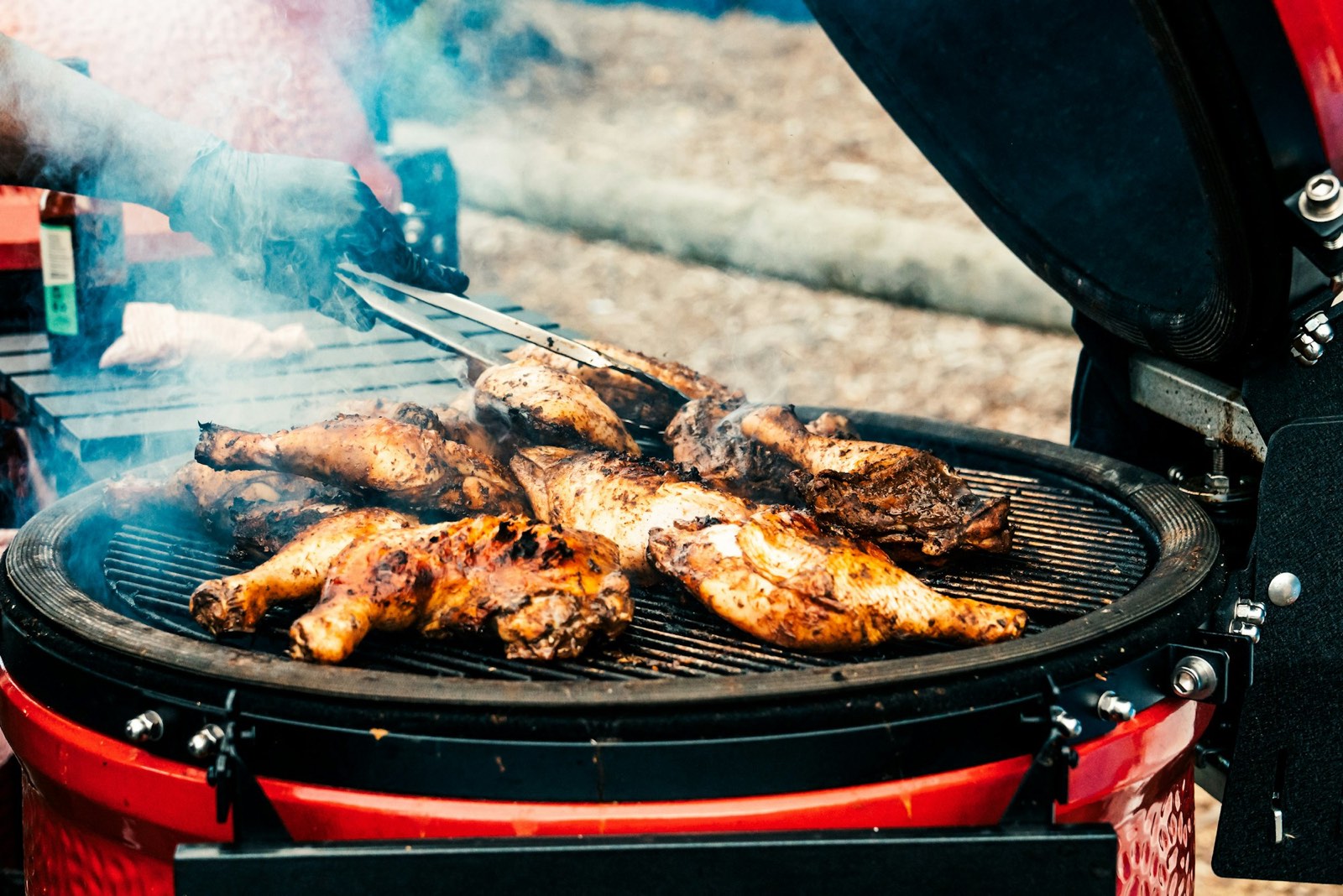 Charred jerk chicken crowded on the drum grill, smoke rising